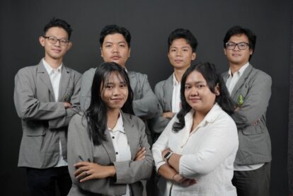 11ftim catrawarta Group portrait of six professionals in gray blazers posing against a dark backdrop