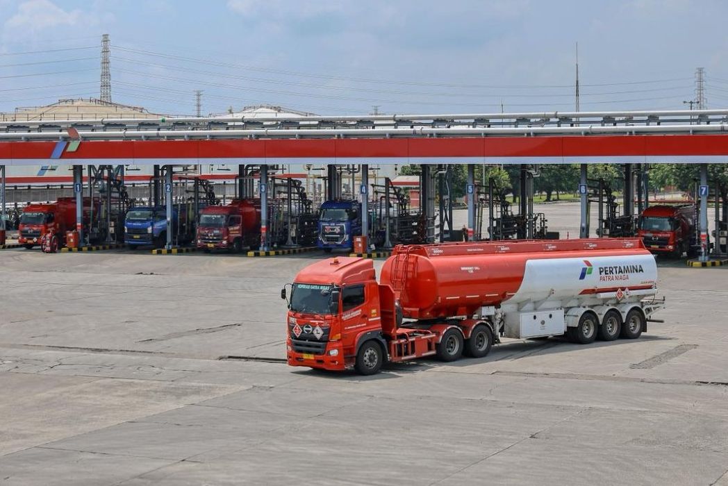 19fpertamina catrawarta Red fuel tanker truck with a white trailer in the foreground at a pertamina fuel depot multiple loading bays and other trucks visible in the background