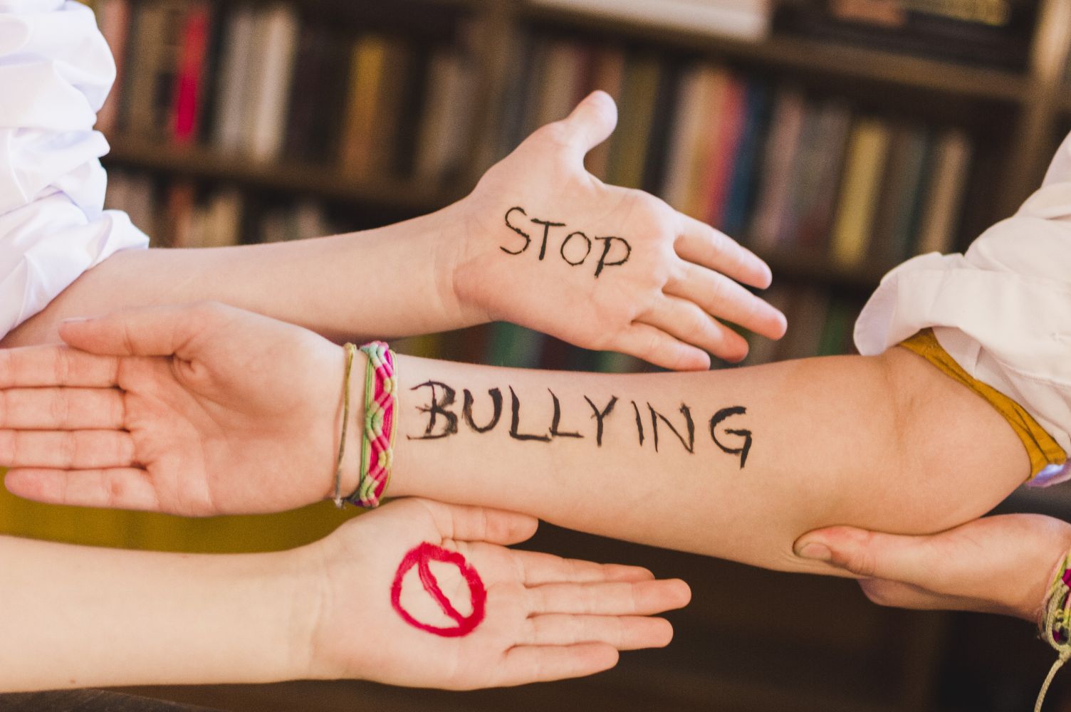 19fstop catrawarta Forearm with stop bullying written in black surrounded by open hands in a supportive pose