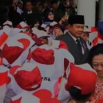 Crowd of people in red and white outfits waving indonesian flags at a public ceremony a smiling woman stands in the foreground