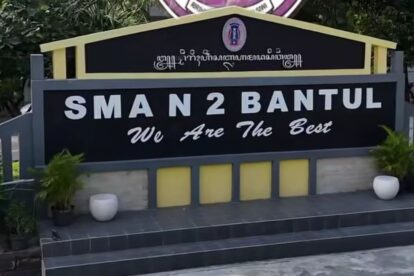 Signboard for SMA N 2 Bantul with the slogan 'We Are The Best' in front of a dark panel and yellow framing.