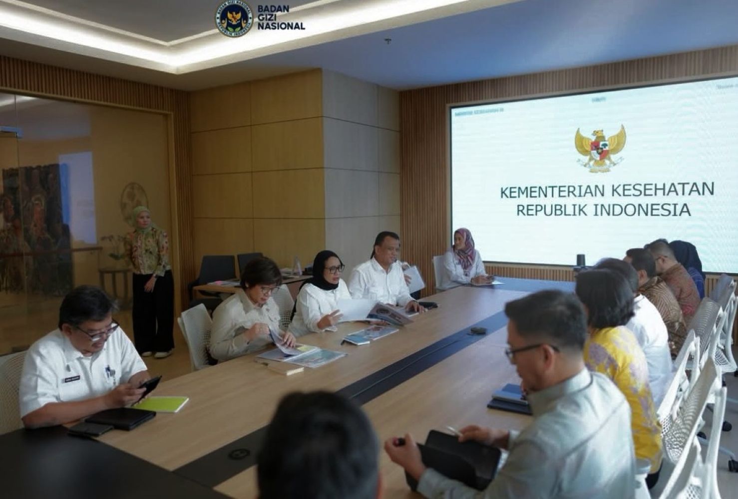 20fbgn catrawarta Officials seated at a long conference table during a kemenkes indonesia meeting with a large screen displaying the ministrys name and emblem in the background
