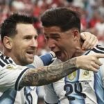 Two argentina players celebrate a goal embracing and shouting with arms around each other on the field