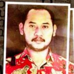 Portrait of a man with a mustache and short dark hair wearing a red patterned shirt framed by a white border against a newspaper like background
