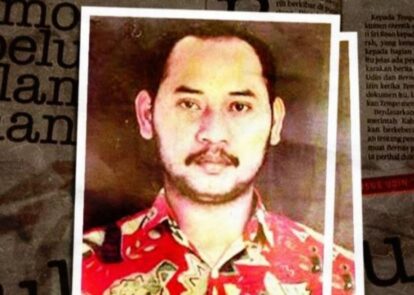 Portrait of a man with a mustache and short dark hair wearing a red patterned shirt, framed by a white border against a newspaper-like background.