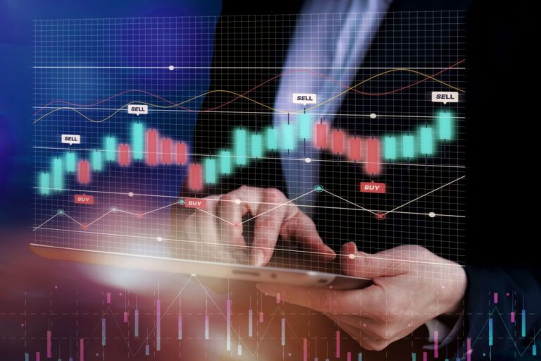 Hands hold a tablet with a glowing stock chart overlay showing green/red candlesticks and buy/sell markers.",