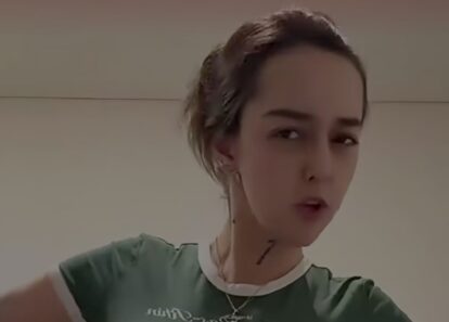 Close-up of a person wearing a green shirt with a white collar, looking at the camera indoors.