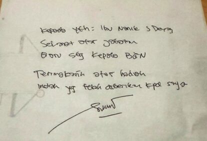 Handwritten note on white paper with a signature at the bottom faint circular doodle on the left edge