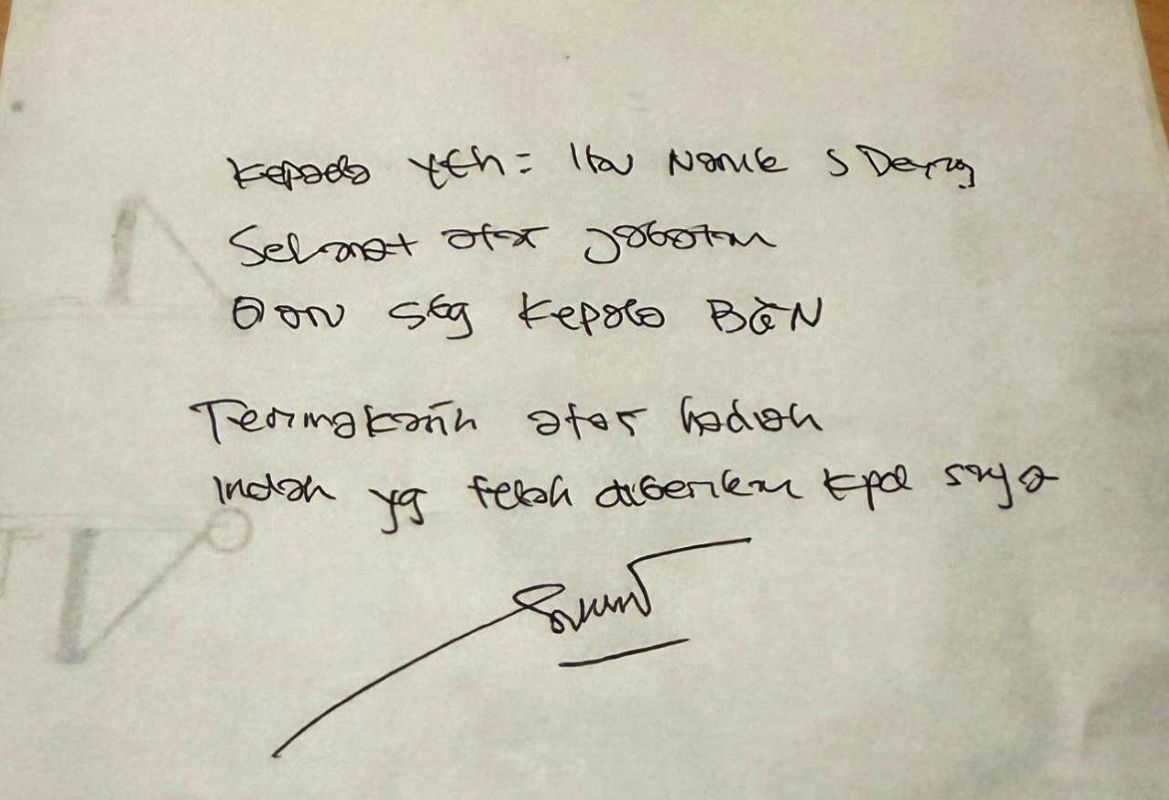Handwritten note on white paper with a signature at the bottom faint circular doodle on the left edge