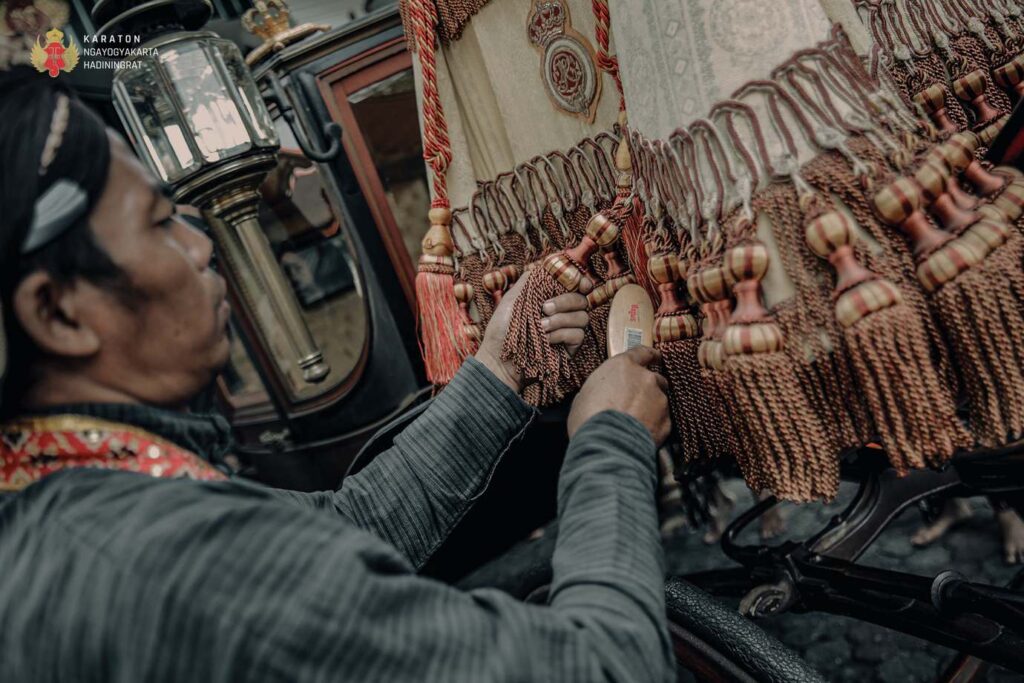6c76ed7484374a788307bdd884640a1c catrawarta An artisan attaching tassels to a woven rug in a market stall showcasing handmade textiles