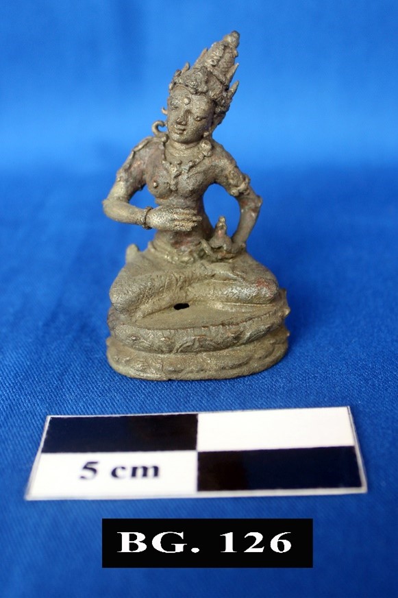 Small seated deity statue with an ornate headdress on a round base scale shows 5 cm and the label bg 126 in the foreground