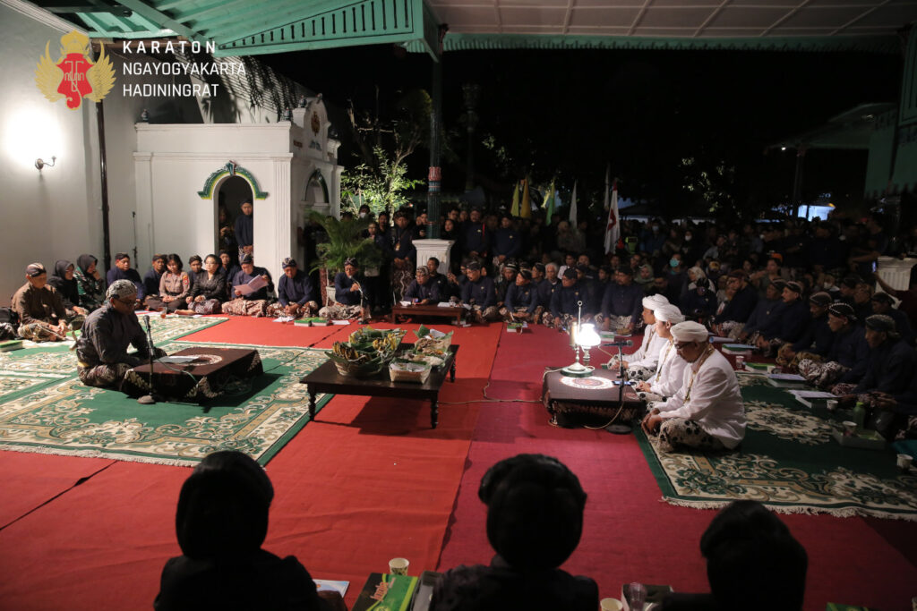 Bed36d2741a04a9382a60bc6b290c546 catrawarta Nighttime ceremonial gathering at the karaton ngayogyakarta hadiningrat with attendees seated on carpets in traditional attire