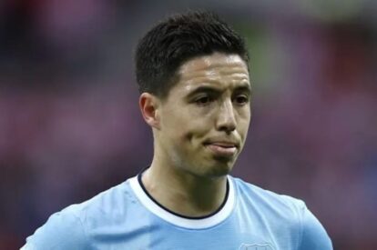 Close-up of a male soccer player in a light blue jersey looking to the right on the field.