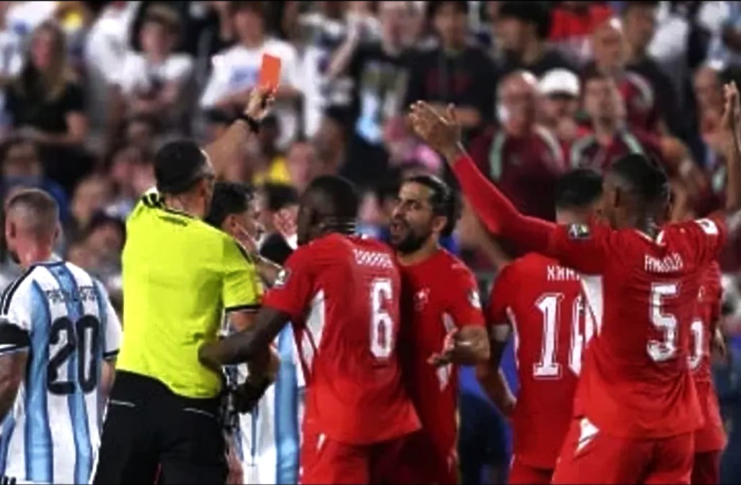 12gwasit catrawarta Redjersey soccer players celebrate surrounding the referee after a decision with fans in the stands in the background