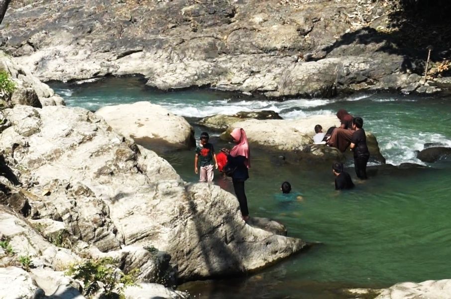 14glava catrawarta Group of people wading in a turquoise river among large gray rocks on a sunny day