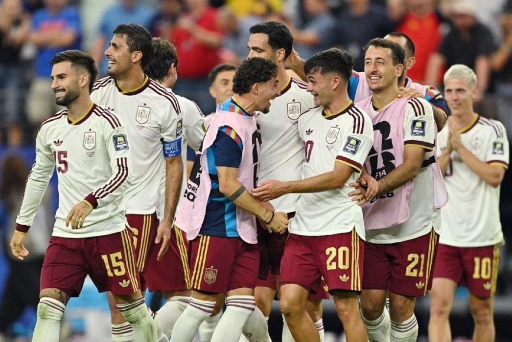 15gspanyol1 catrawarta Group of soccer players in white jerseys and maroon shorts celebrate together on the field smiling and embracing each other