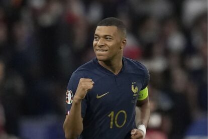 French footballer wearing a navy France jersey with number 10, fist pumped in celebration.