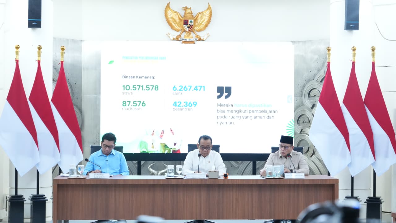 17847019756a60641753d96 catrawarta Official briefing or press conference with three men at a long desk indonesian flags on both sides and garuda pancasila crest above a presentation screen
