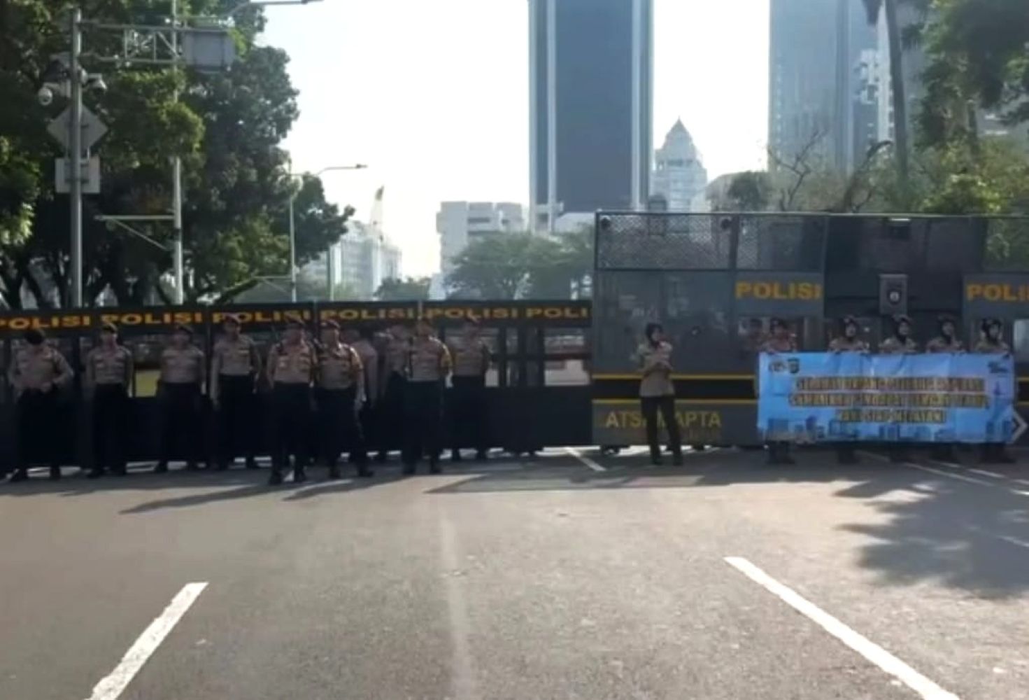 17gdemo catrawarta Line of uniformed police officers standing behind a barricade across a city street blocking traffic with polisi signage visible
