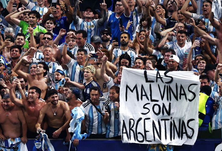 17gmalvinas catrawarta Crowd of argentine soccer fans in striped shirts cheer with raised arms holding a banner that reads las malvinas son argentinas