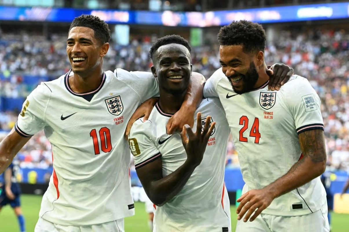 19gsaka1 catrawarta Three england players celebrate together on the pitch smiling with arms around each other after a goal stadium cheering in the background