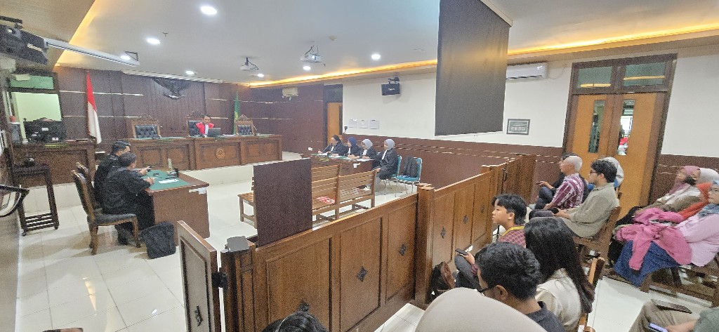 Courtroom scene with a judge at the bench indonesian flag visible and attendees watching the proceedings