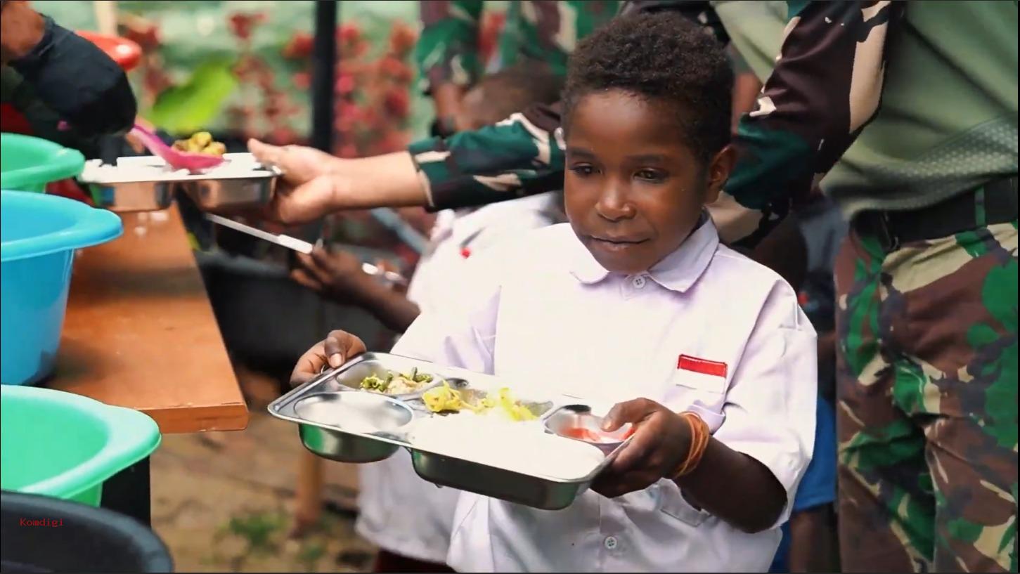 2521img20250219wa0014 catrawarta Schoolgirl in a white uniform holds a metal lunch tray with compartments in a crowded outdoor meal line