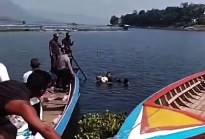 People on a colorful boat watching a person swimming or rescuing in calm water near the shore