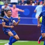 French soccer players celebrate a goal central player wearing number 10 clenches a fist with teammates nearby in blue kits