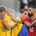 A tense moment on the field a yellow jerseyed player number 16 covers his face as teammates restrain him while a red jerseyed player number 10 reaches toward him