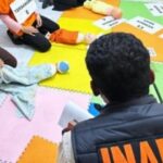 Suspects kneeling on colorful foam mats with signs reading tersangka and numbers under police supervision