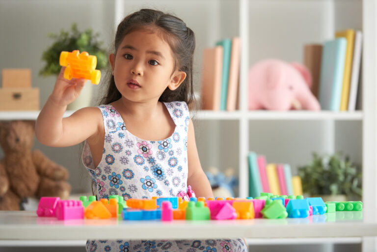 Anak sedang bermain dan belajar menggunakan mainan di atas meja.