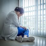 Ilustrasi dokter yang mengalami tekanan mental dan depresi sedang duduk merenung di atas lantai rs