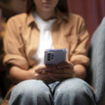 Perempuan melihat ke layar hp dengan terpukul dan sedih