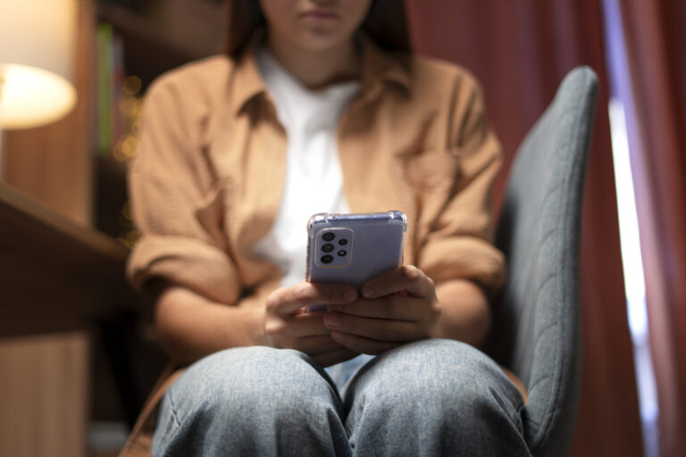 Perempuan melihat ke layar hp dengan terpukul dan sedih.