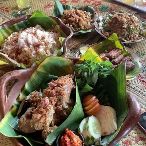 Banana leaf platter with coconut rice crispy fried fish and assorted indonesian side dishes