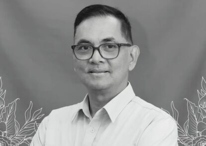 Obituary banner with a man in a light shirt and glasses on a blue gradient background with a cross and indonesian memorial text