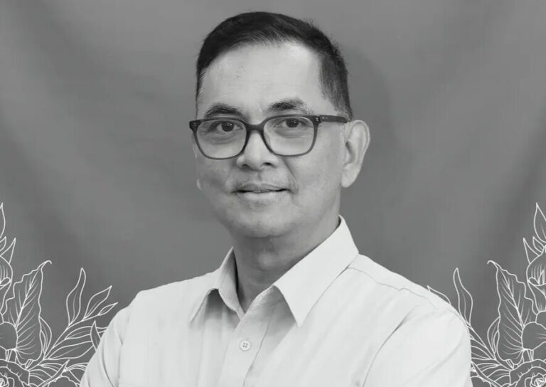 Obituary banner with a man in a light shirt and glasses on a blue gradient background with a cross and Indonesian memorial text.
