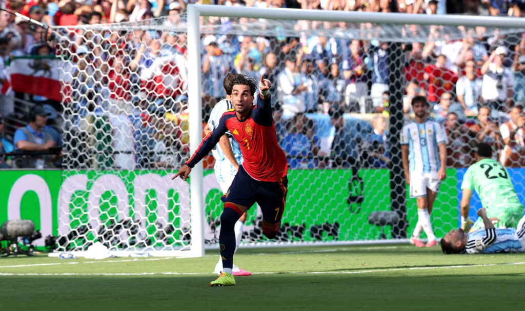 Spainvargentinafinalfifaworldcup2026 1 catrawarta Soccer player in red and blue celebrates near the goal as fans cheer in the stands behind him