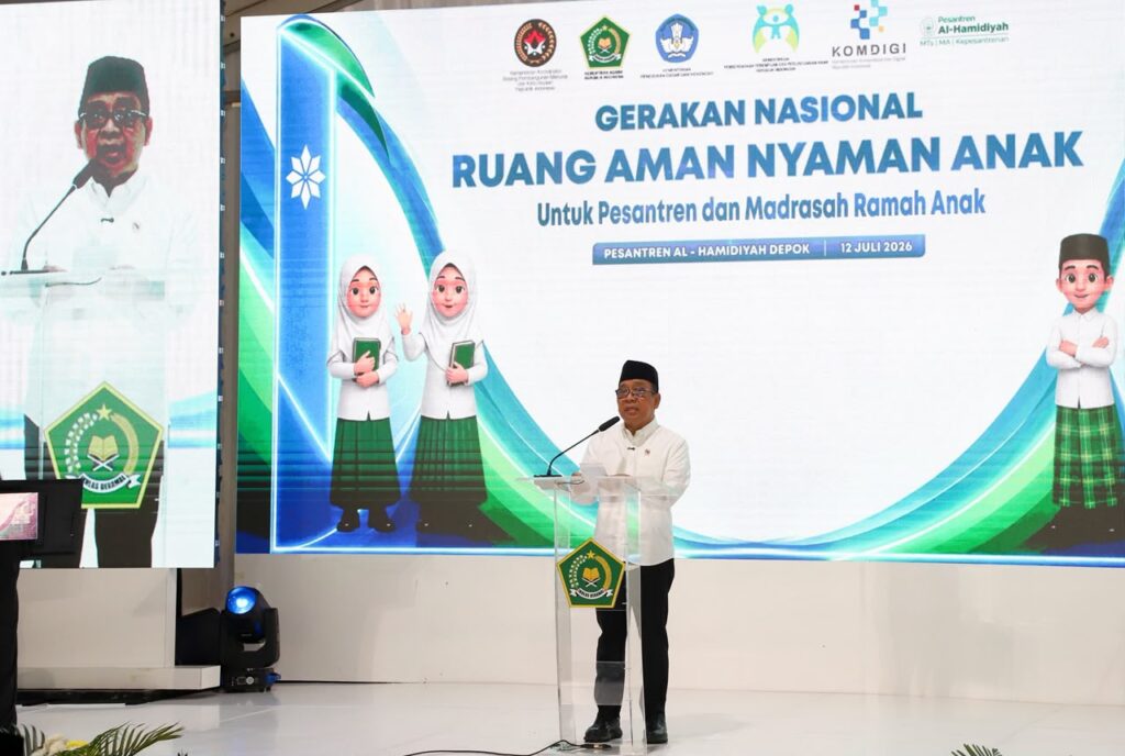 Menko pmk pratikno catrawarta Man in a white shirt and cap speaks at a clear podium during a formal event with a large banner about a national program for safe spaces for children in the background